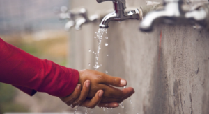 Child's hand under water faucet.