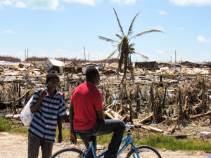 men looking at hurricane dorian destruction